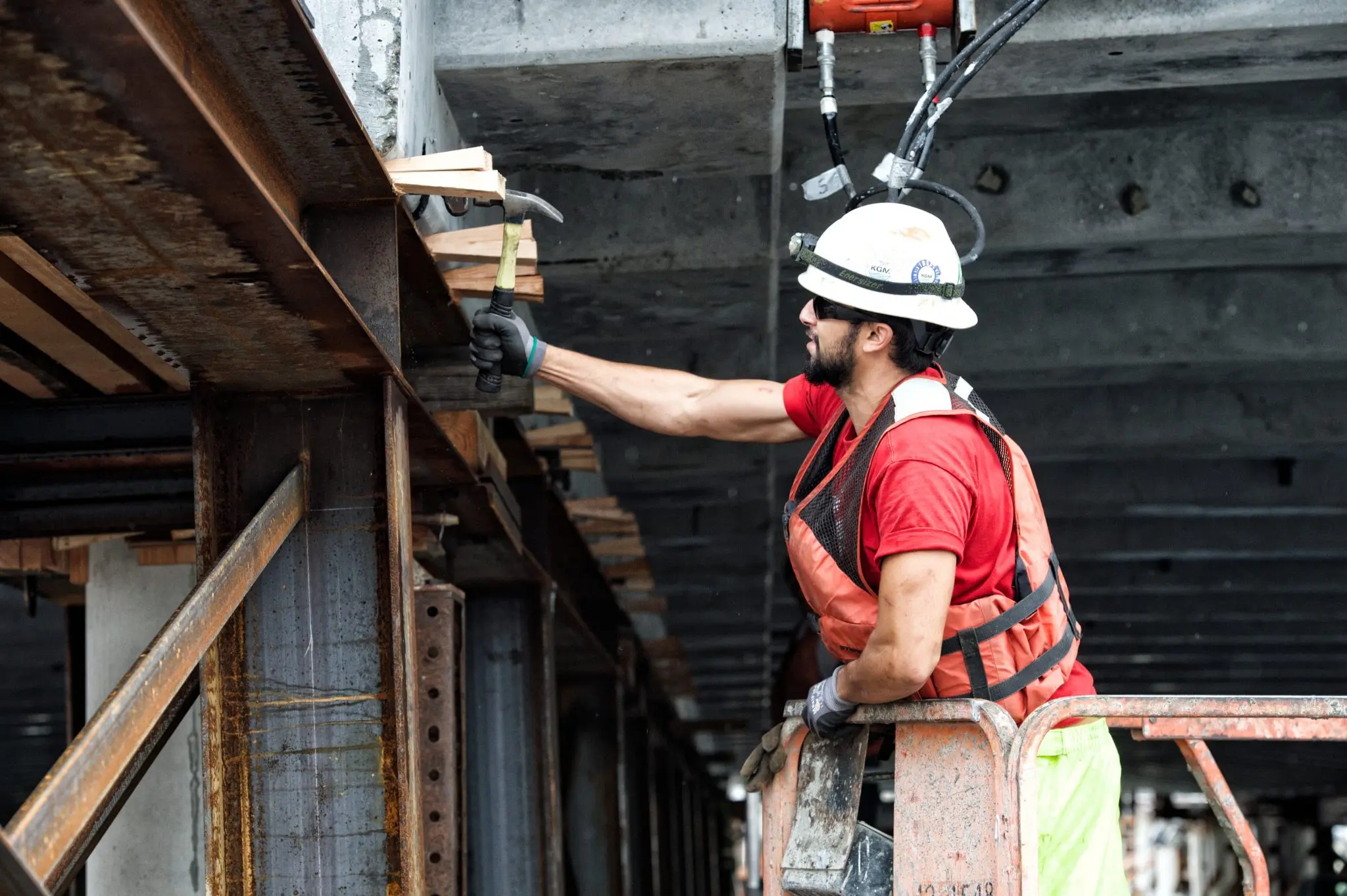 Construction crew in lift with hammer, wearing safety gear