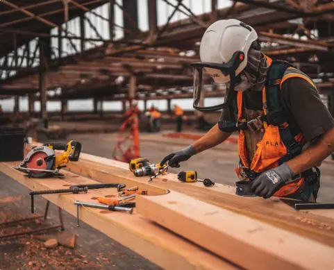 Crew member working with wood planks, wearing safety gear
